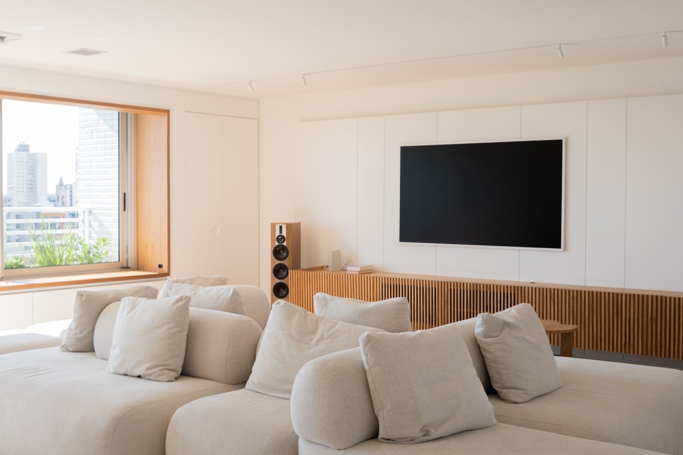 Phòng khách tông ấm trung tính với gỗ và sofa lớn, tạo cảm giác sáng dịu nhưng vẫn có chiều sâu